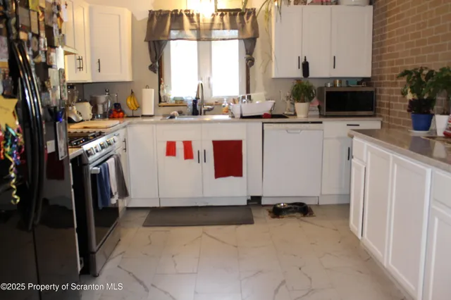 a utility room with stainless steel appliances a stove a sink and a refrigerator