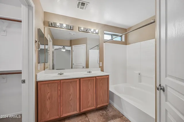 a bathroom with a bathtub a double vanity sink and mirror