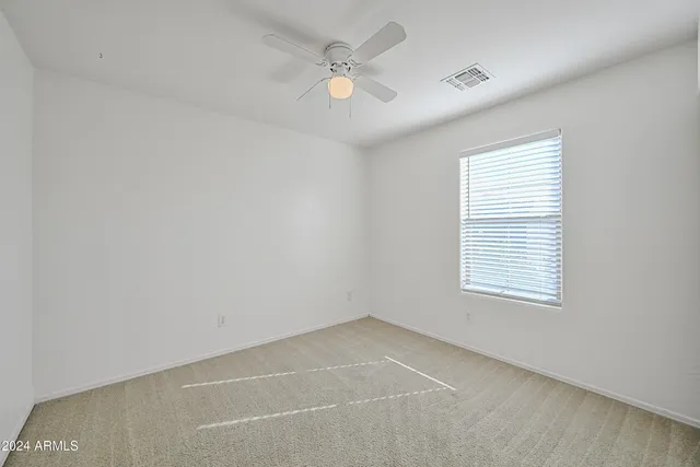 an empty room with a window and a ceiling fan