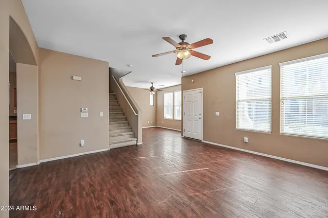 a view of empty room with wooden floor and fan