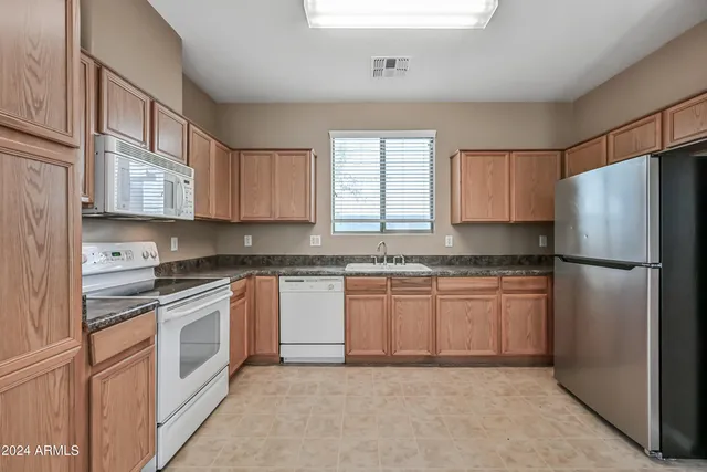 a kitchen with granite countertop stainless steel appliances a refrigerator sink and cabinets