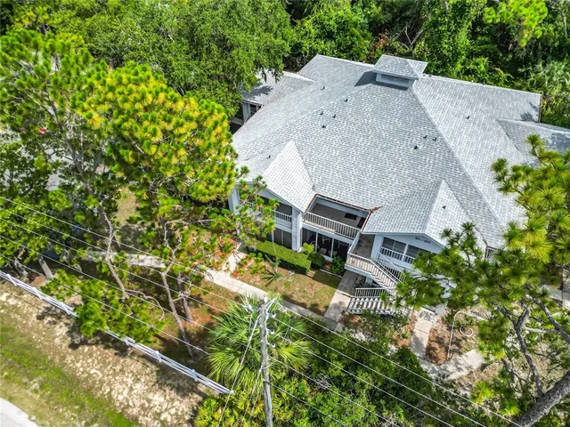 an aerial view of a house with a yard and trees all around