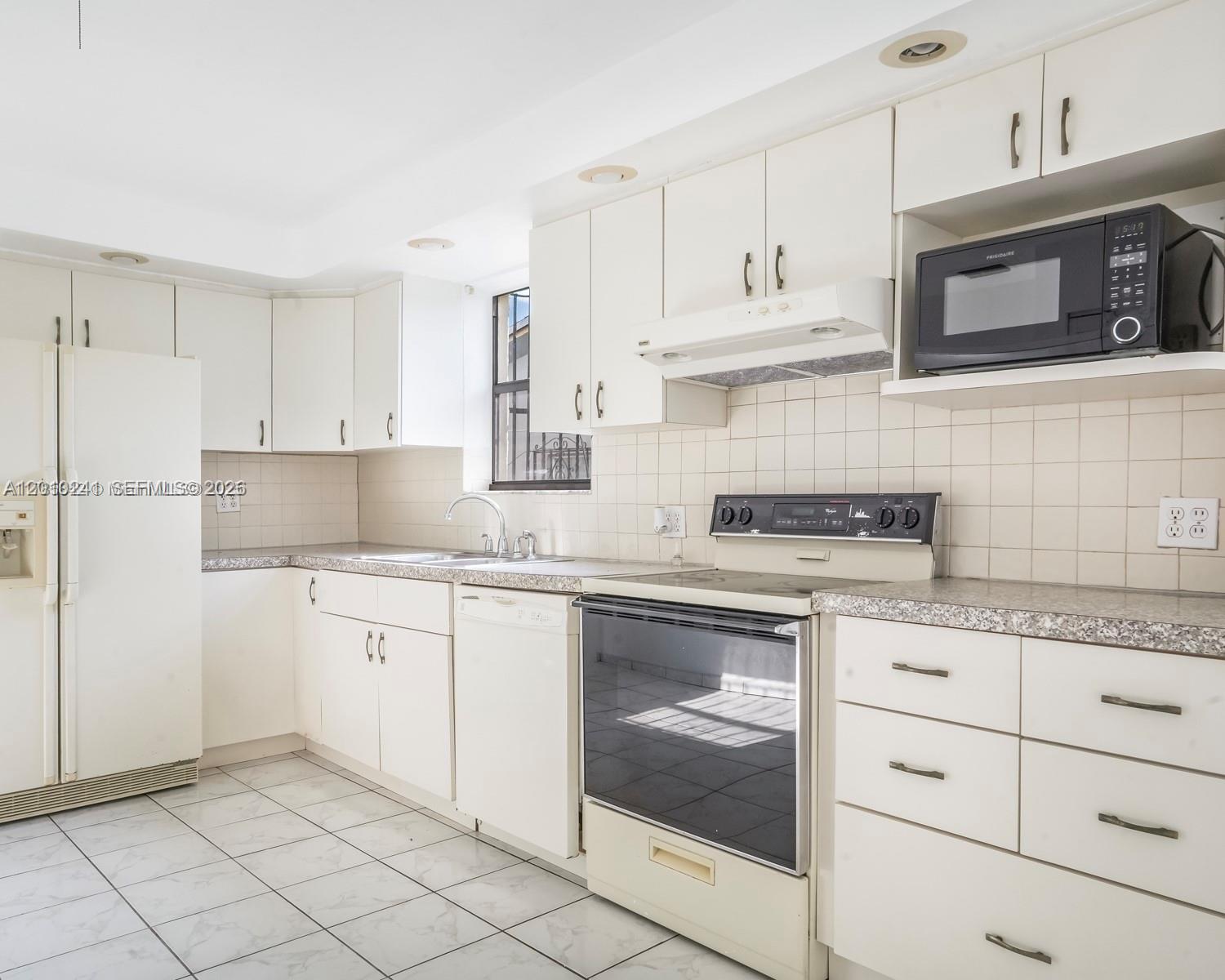 5629 Southwest 7th Street Miami, FL 33144 - Photo 9 of 15 a kitchen with granite countertop white cabinets stainless steel appliances and a sink