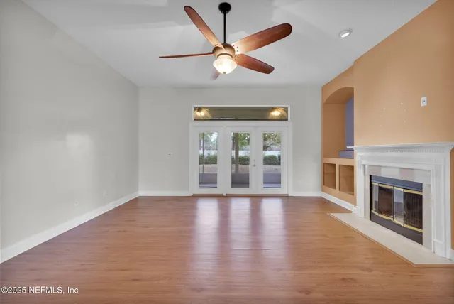 a view of an empty room with wooden floor and a fireplace