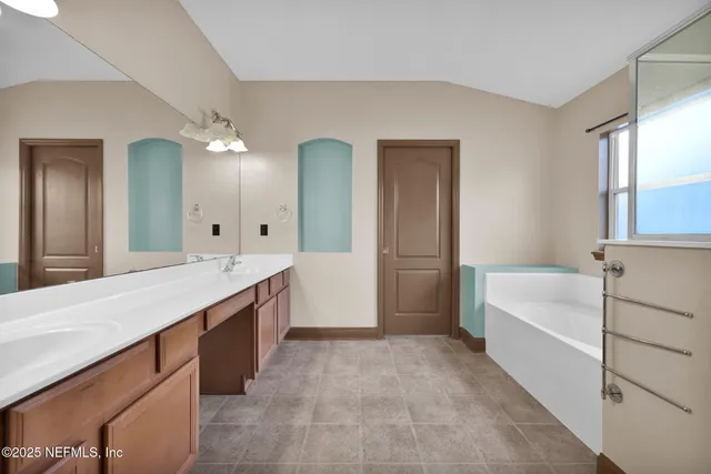 a spacious bathroom with a bathtub sink and mirror