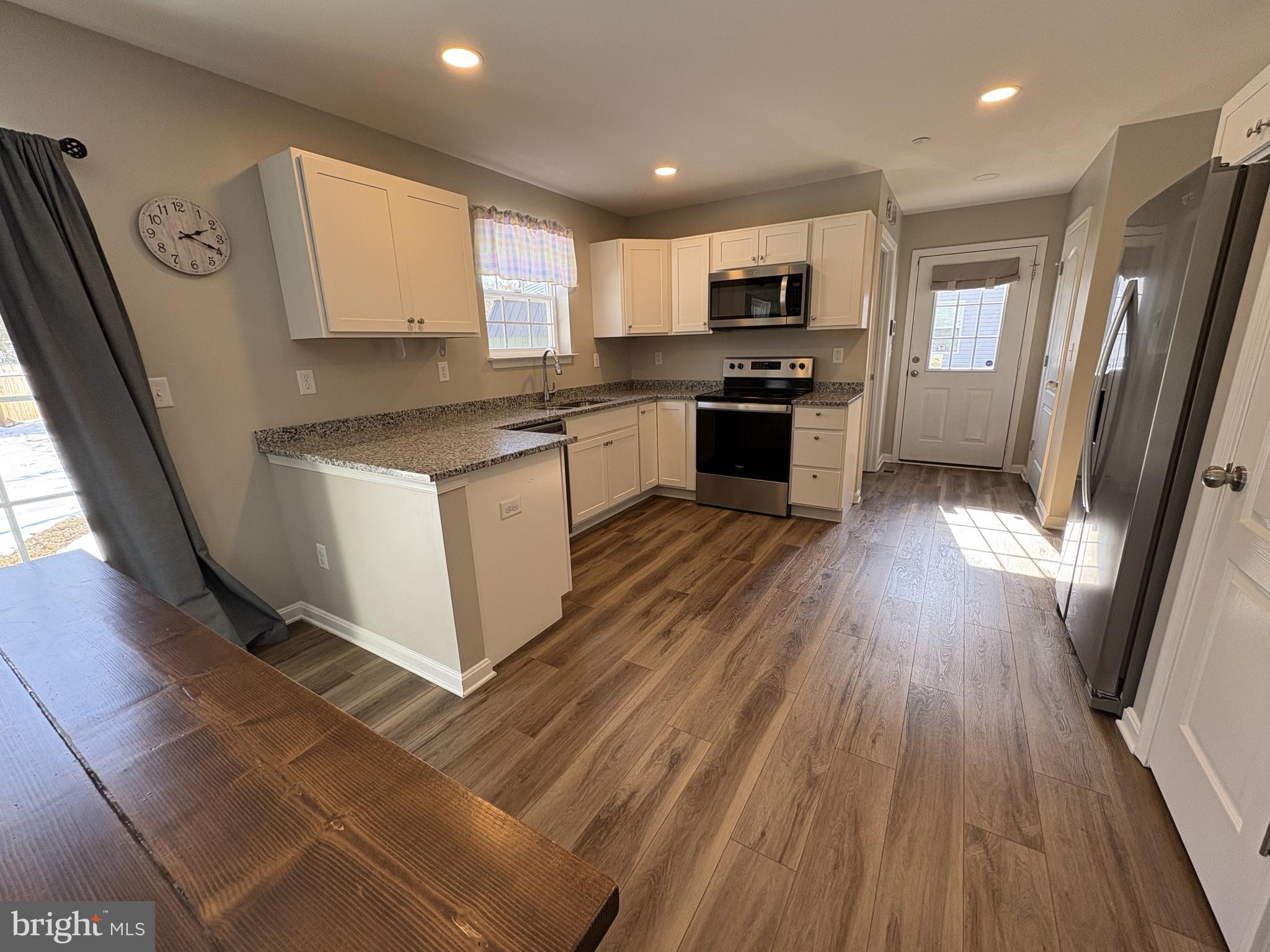 148 East Step Road Chestertown, MD 21620 - Photo 7 of 46 a kitchen with granite countertop a refrigerator a sink dishwasher a stove and white countertops with wooden floor