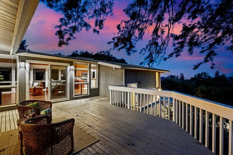 a view of a house with wooden deck front of house