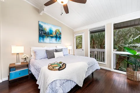 a bedroom with a large bed a large window with wooden floor