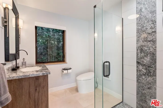 a bathroom with a granite countertop sink a toilet and shower