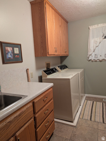 1040 West Mill Road Ferron, UT 84523 - Photo 27 of 117 Functional laundry space featuring wood-finish cabinetry, a utility sink with a laminate countertop, and tile flooring