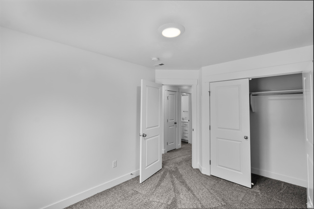 3014 South 265th Street West Logan, UT 84321 - Photo 10 of 25 Carpeted room with white walls, a flush-mount ceiling light, and a two-panel sliding closet door with an interior hanging rod