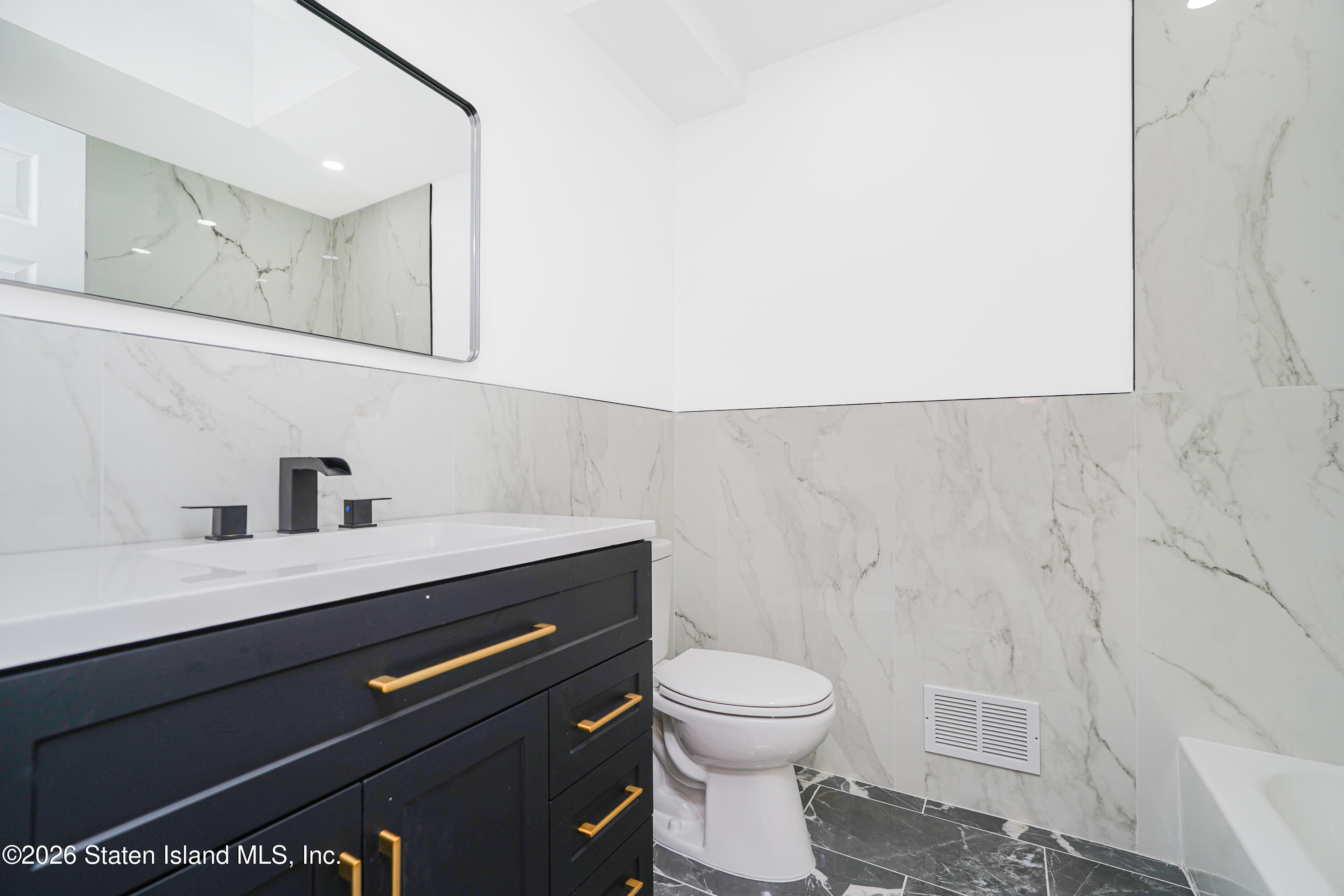 48 Studio Lane Staten Island, NY 10304 - Photo 21 of 38 a bathroom with a sink a toilet and a mirror