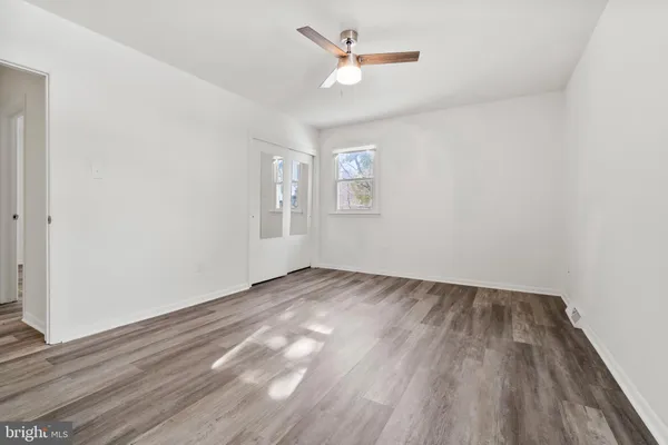 an empty room with wooden floor ceiling fan and windows