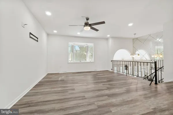an empty room with wooden floor fan and windows