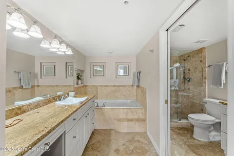 a spacious bathroom with a granite countertop double vanity sink a mirror and a shower