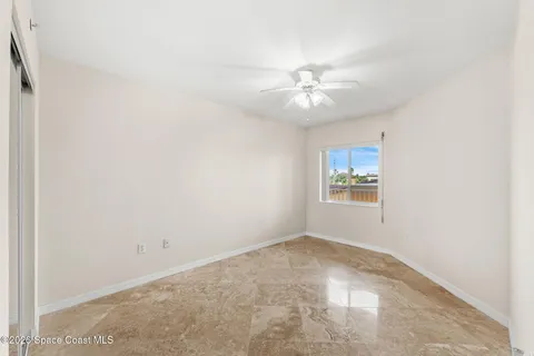 an empty room with a fan & a window