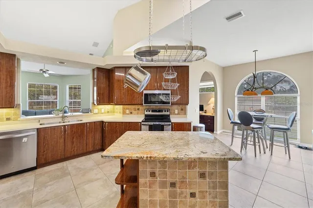 a kitchen with stainless steel appliances granite countertop a sink a stove top oven a counter space and cabinets