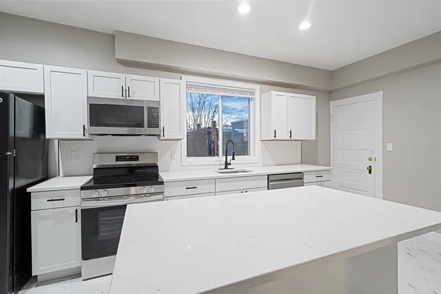 a kitchen with stainless steel appliances a stove microwave and sink