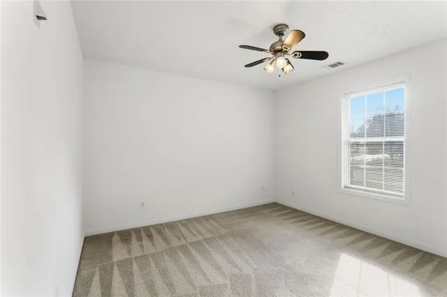 an empty room with window and ceiling fan