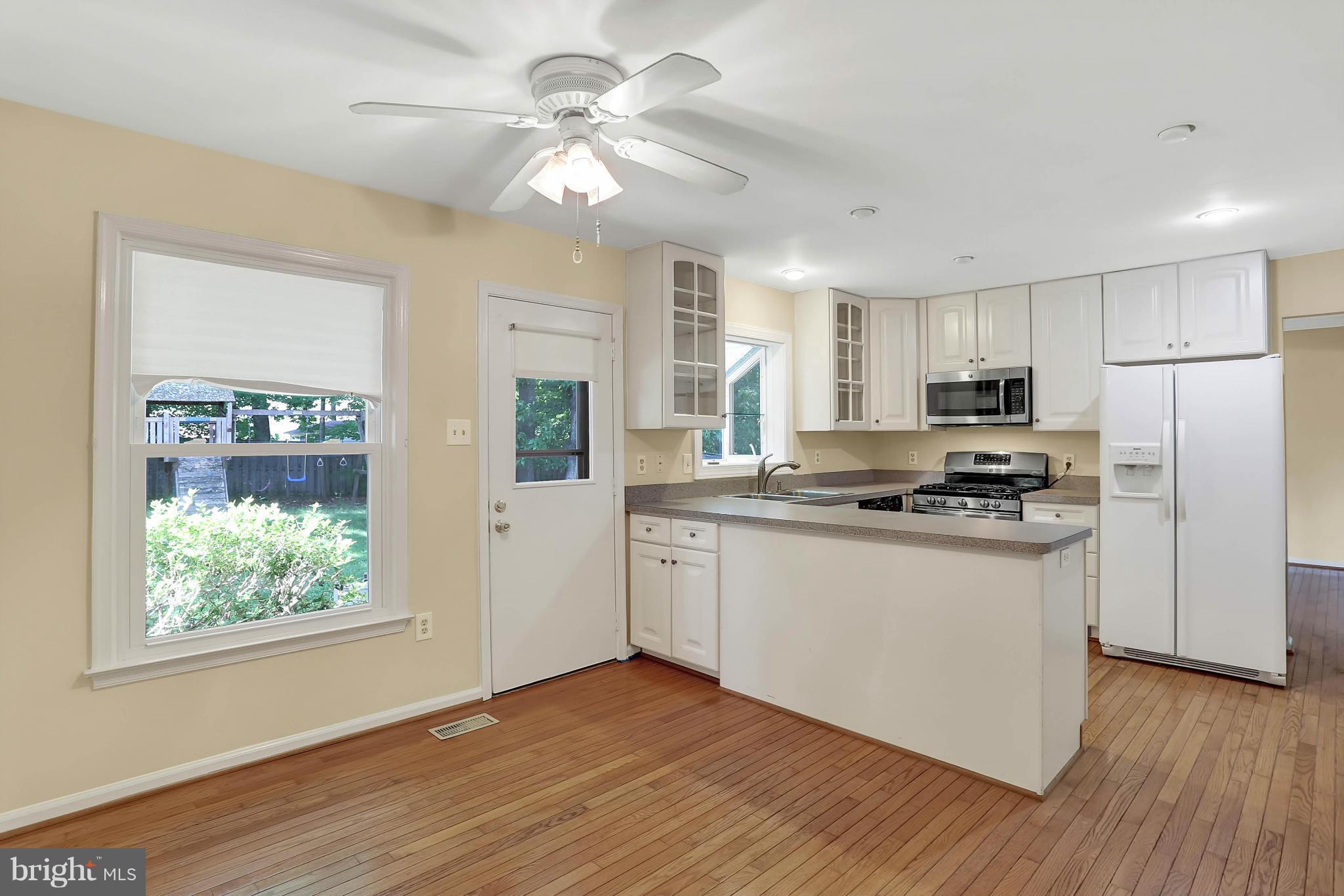 9160 Rockefeller Lane Springfield, VA 22153 - Photo 10 of 27 a kitchen with stainless steel appliances granite countertop a refrigerator a stove top oven a sink with wooden floors and white cabinets