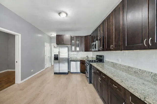 a kitchen with stainless steel appliances granite countertop a stove a sink and a refrigerator