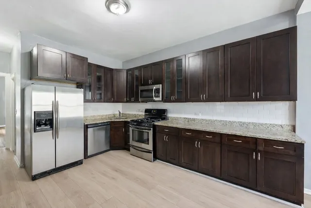 a kitchen with stainless steel appliances granite countertop a refrigerator a sink a stove and oven