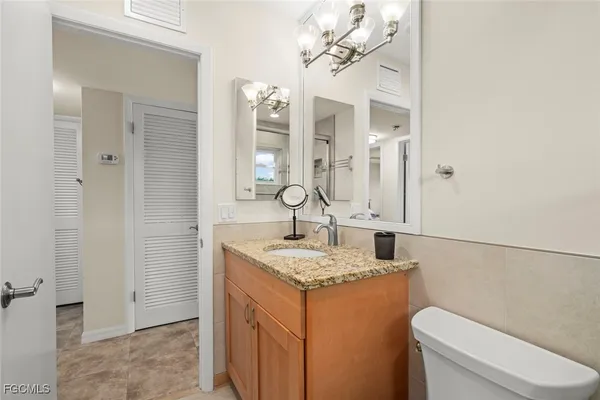 a bathroom with a granite countertop sink a toilet and a mirror