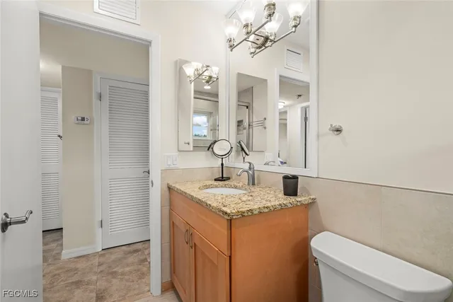 a bathroom with a granite countertop sink a toilet and a mirror