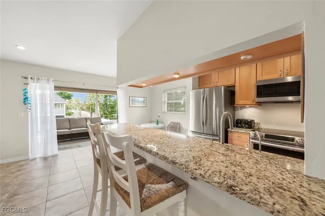 a kitchen with stainless steel appliances granite countertop a stove refrigerator and a view of living room