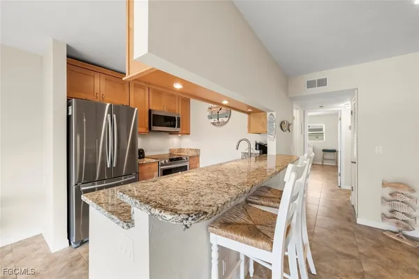 a kitchen with granite countertop a refrigerator and microwave