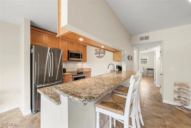 a kitchen with granite countertop a refrigerator and microwave