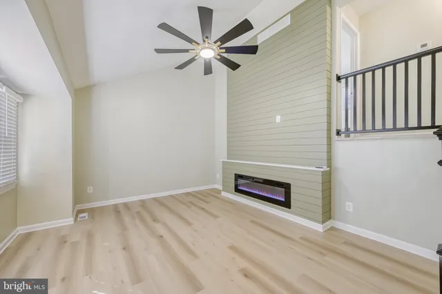 an empty room with wooden floor fan and windows