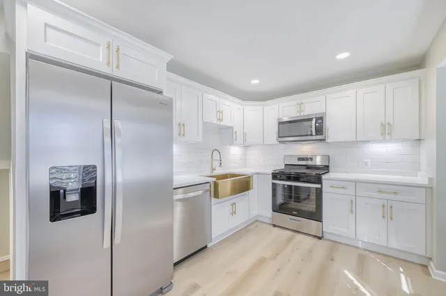 a kitchen with stainless steel appliances granite countertop a refrigerator a stove a sink and white cabinets