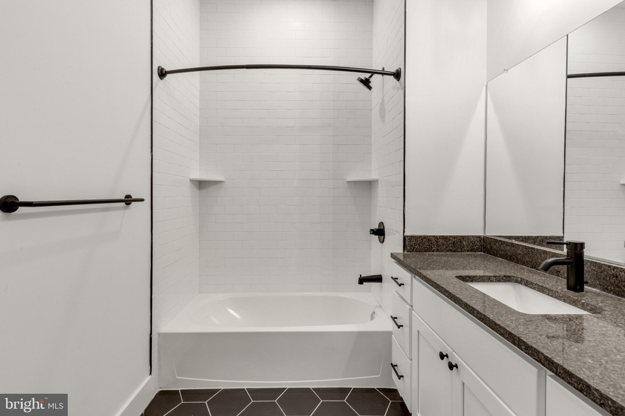 2214 North Front Street, Unit 101 Philadelphia, PA 19133 - Photo 12 of 22 a bathroom with a granite countertop bathtub shower sink and mirror