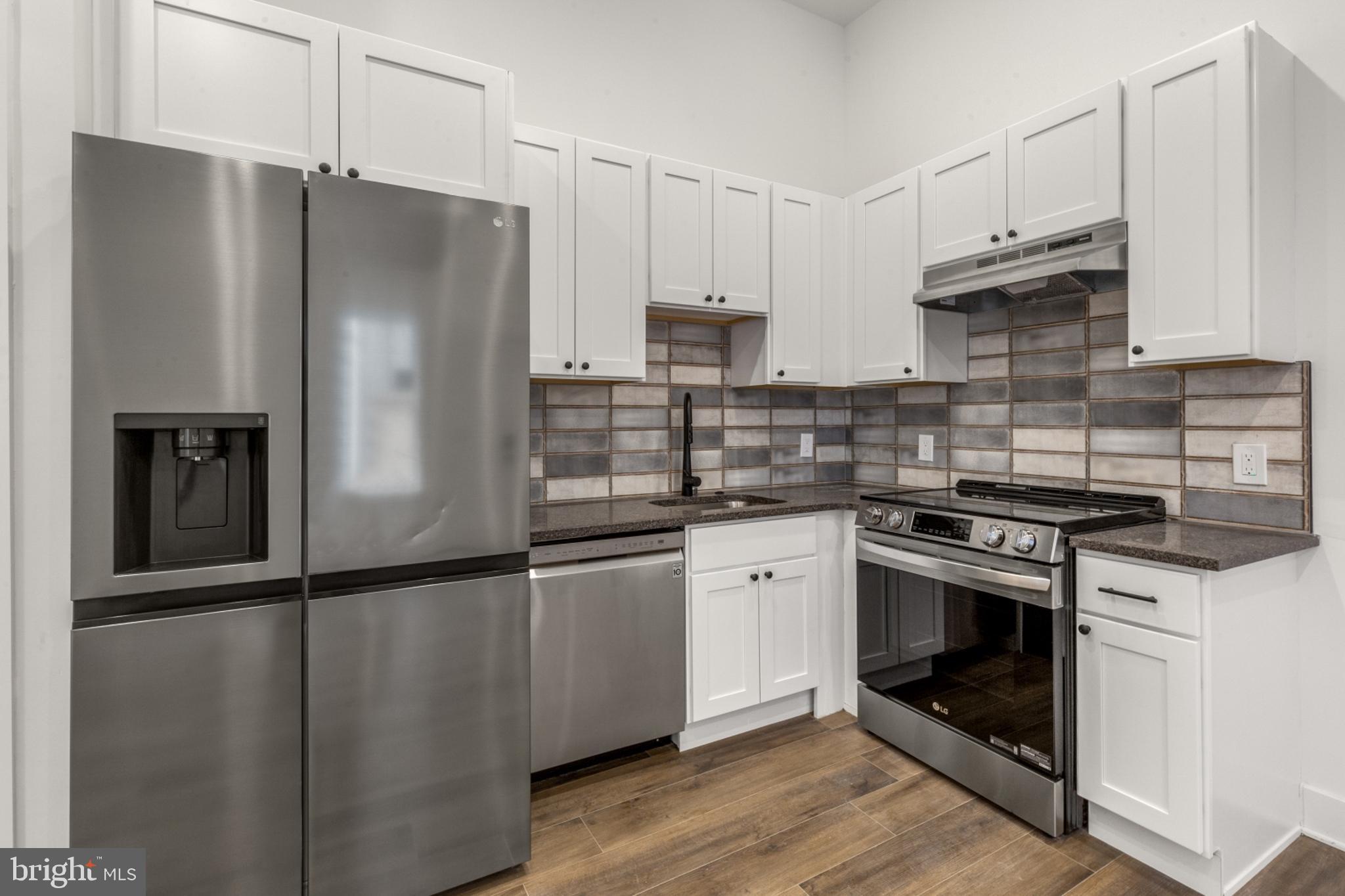 2214 North Front Street, Unit 101 Philadelphia, PA 19133 - Photo 4 of 22 a kitchen with granite countertop a refrigerator stove and sink