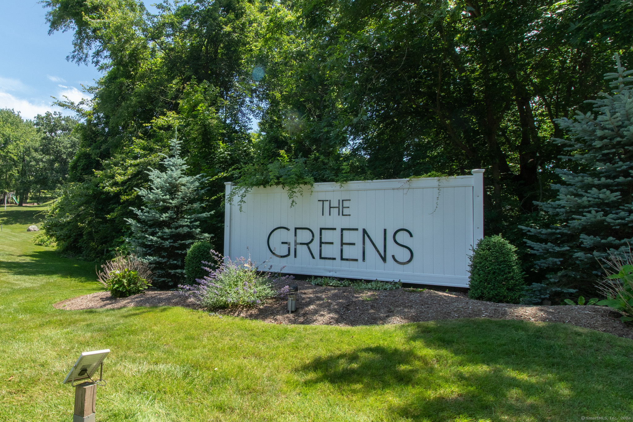 a sign that is sitting in the grass near a tree