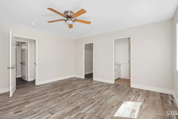 an empty room with wooden floor and ceiling fan