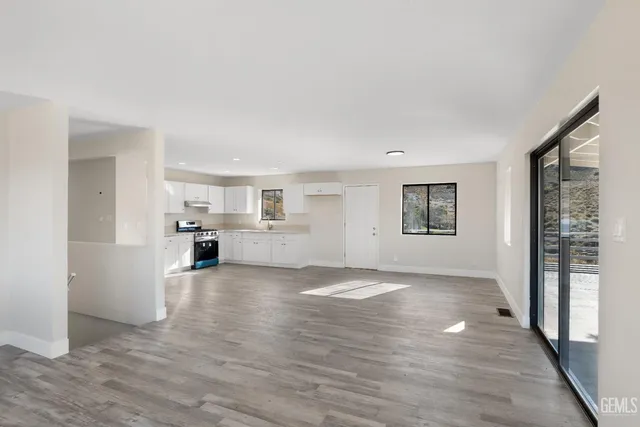 a view of a livingroom with wooden floor and a kitchen