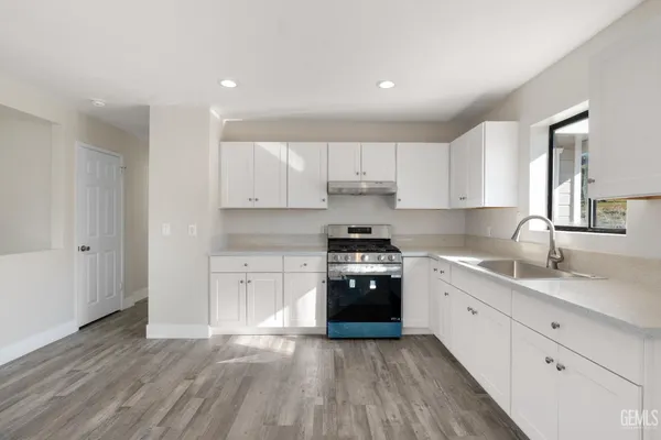 a large kitchen with granite countertop a stove top oven a sink and dishwasher with wooden floor
