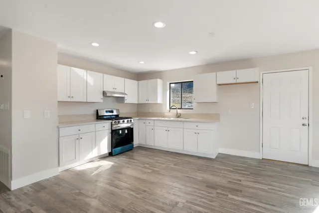 a kitchen with granite countertop white cabinets and stainless steel appliances
