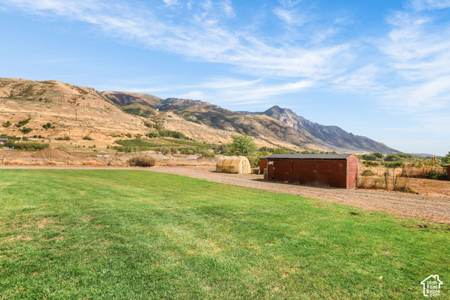 1045 West 3600th South Perry, UT 84302 - Photo 49 of 57 Expansive grassy area with a red outbuilding and a rounded storage structure, set against a mountainous backdrop