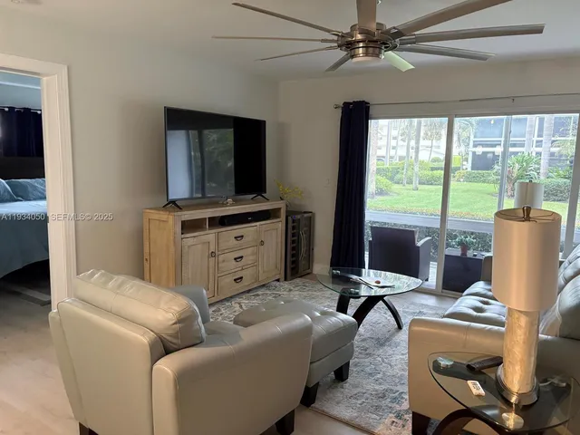 a living room with furniture a floor to ceiling window and a flat screen tv