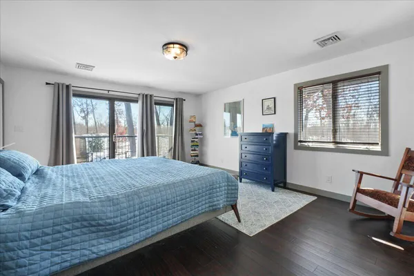 a bedroom with a bed windows and a dresser