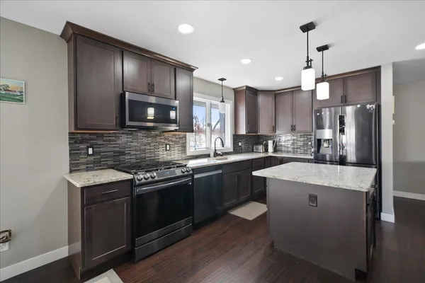 a kitchen with stainless steel appliances kitchen island granite countertop a stove sink refrigerator and cabinets