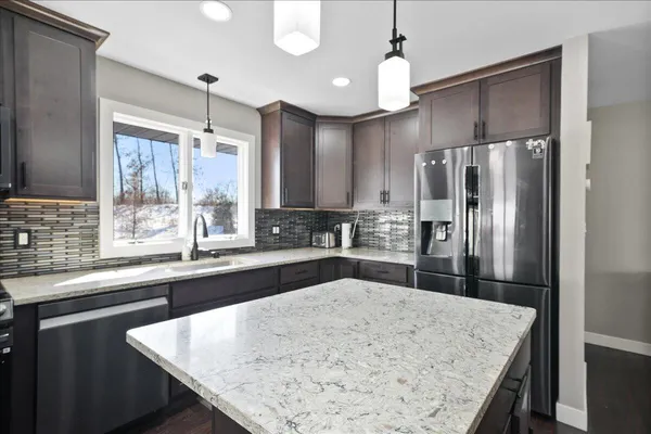 a kitchen with stainless steel appliances kitchen island granite countertop a sink refrigerator and cabinets