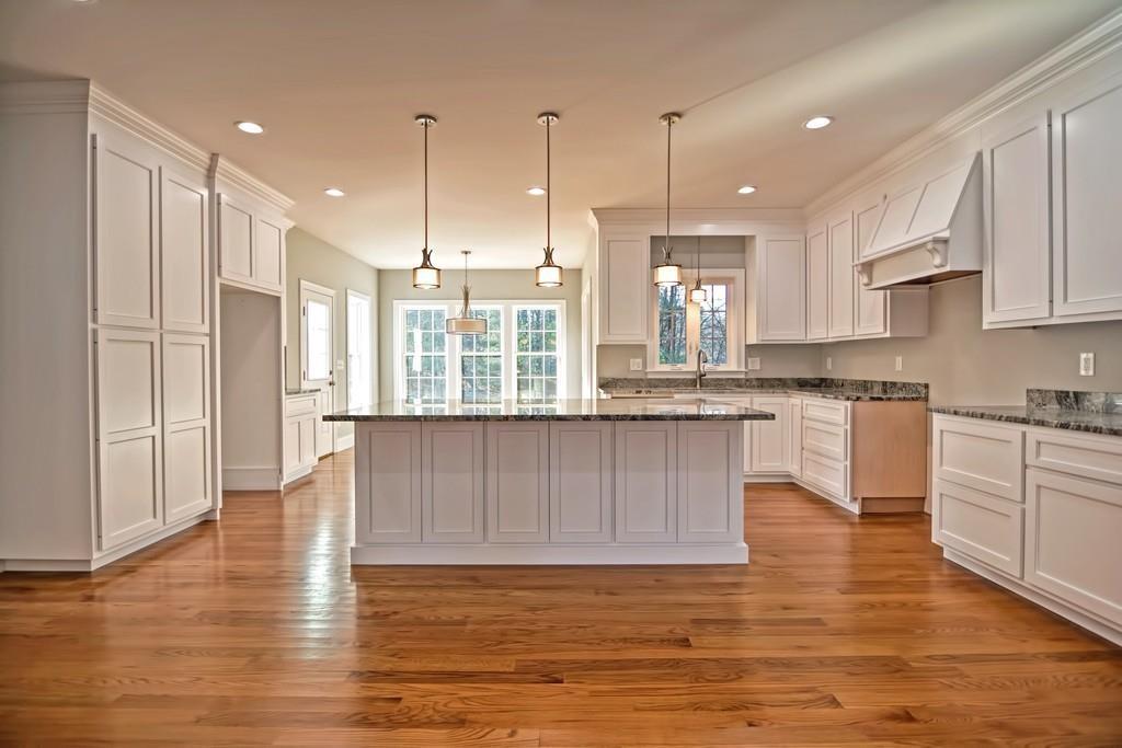 115 High Street Medfield, MA 02052 - Photo 15 of 42 a kitchen with kitchen island granite countertop wooden floors white cabinets and stainless steel appliances