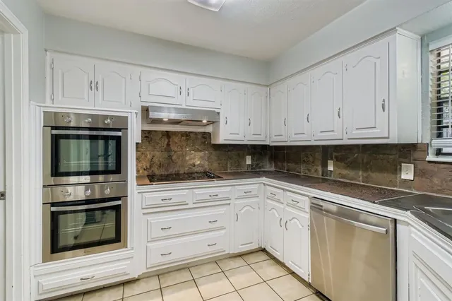a kitchen with white cabinets and stainless steel appliances