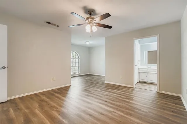 an empty room with wooden floor and ceiling fan