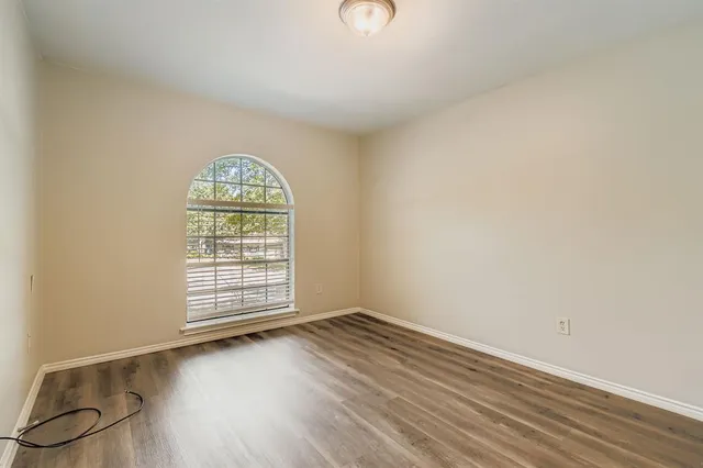 an empty room with wooden floor cabinet and windows