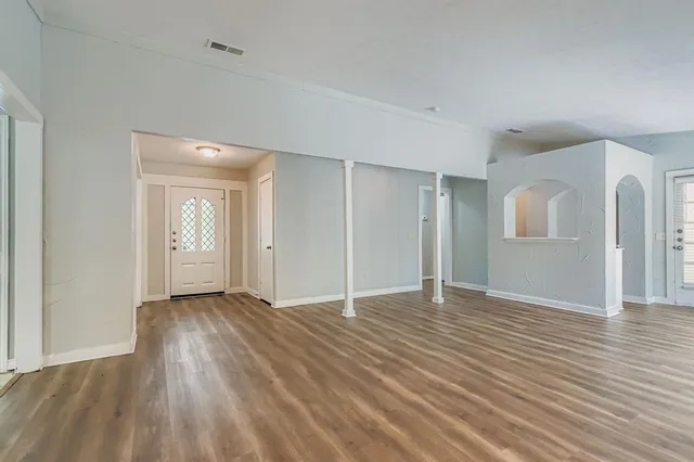 a view of an empty room with wooden floor and a window